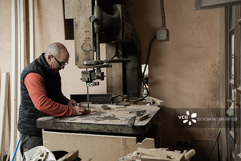 穿着工作服的中年木匠在木工车间使用锯床图片素材