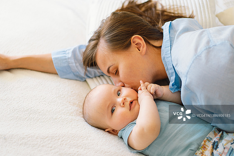 一位年轻的母亲正在和一个小男孩玩。哺乳期婴儿的母亲图片素材