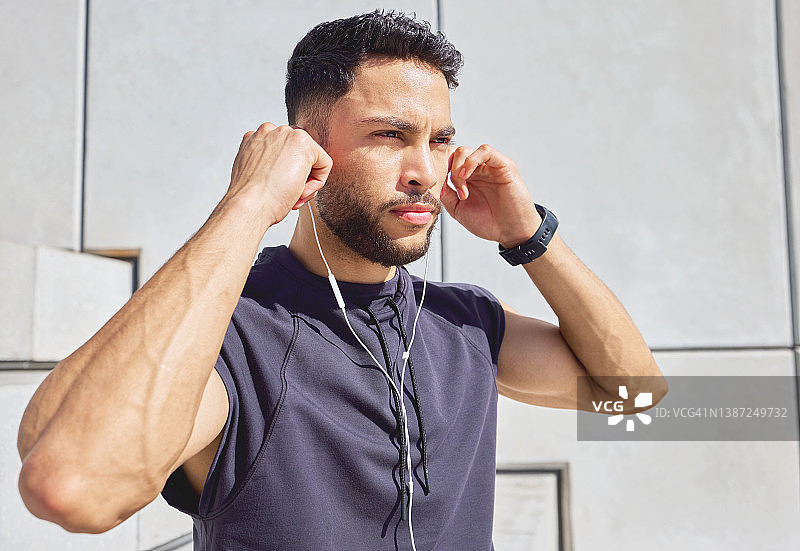 一个运动的年轻人一边听音乐一边在户外锻炼图片素材
