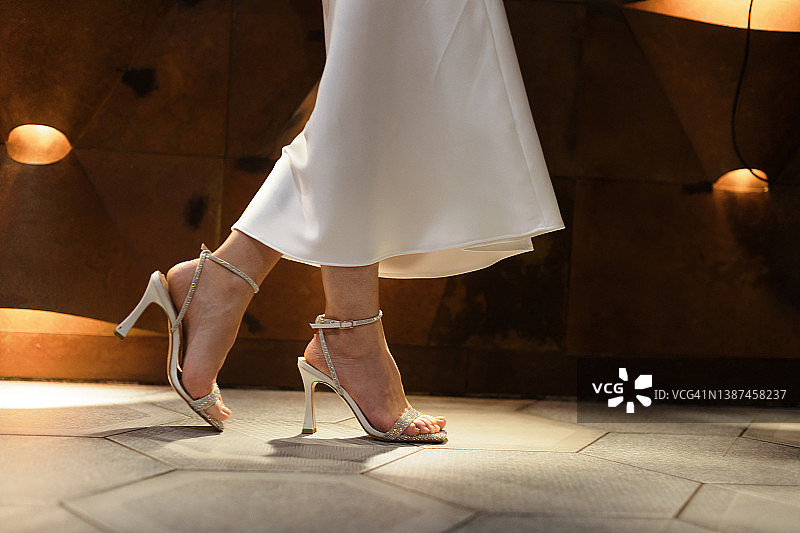 低角度的观点，妇女在高跟鞋和白色的连衣裙行走。图片素材