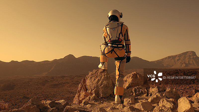 火星漫步。女宇航员探索生锈的山脉。爬上岩石图片素材
