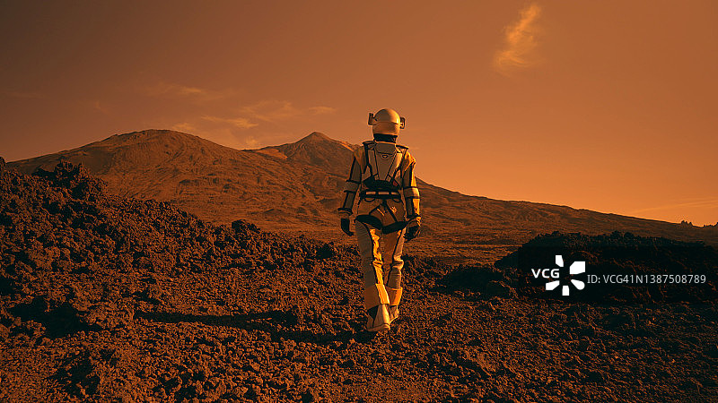 火星漫步。女宇航员探索铁锈色沙漠。走向山脉图片素材