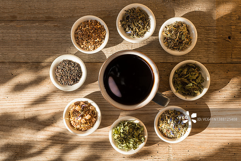 不同种类的茶或草药在一个古老的桌子上碗与一杯茶在日落图片素材