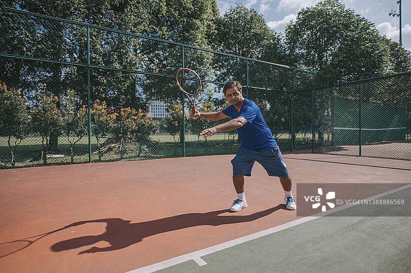 亚洲印度男性网球教练，旨在显示正确的姿势在网球场上图片素材