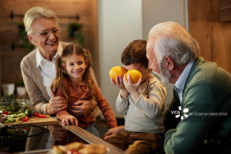 快乐的祖父母和他们的孙子在厨房里玩得很开心。图片素材