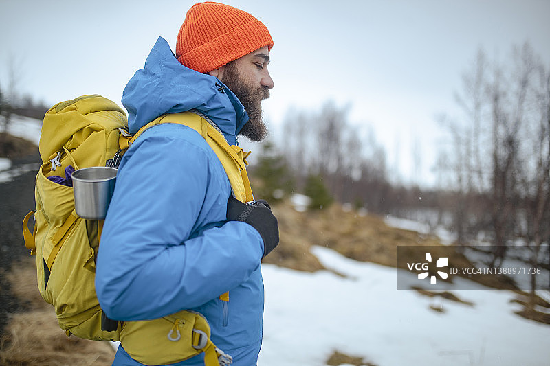一名游客在徒步旅行时穿着全套冬季装备的侧视图。ISL图片素材