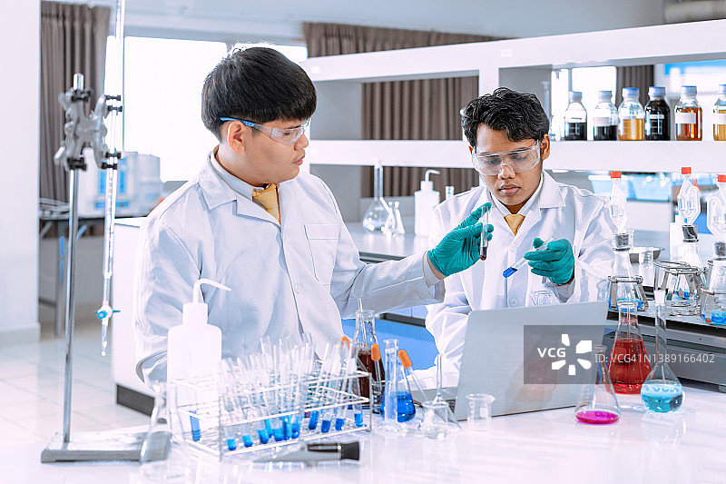 在实验室工作的年轻亚洲男性科学家。医生和科学家在实验室工作的冠状病毒大流行，covid - 19概念图片素材