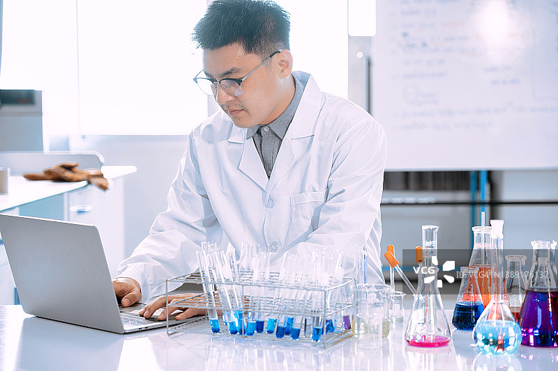 年轻的亚洲男子科学家在实验室工作的肖像。医生和科学家在实验室工作的冠状病毒大流行，covid - 19概念图片素材