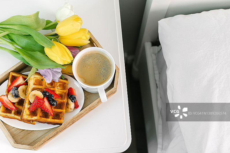假日早餐俯视图。美味的分店-咖啡，比利时浆果华夫饼，红色礼盒和新鲜郁金香图片素材