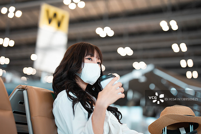一名年轻女子在国际机场等待航班时，一边阅读电子书，一边喝咖啡。女乘客在候机楼，室内。图片素材