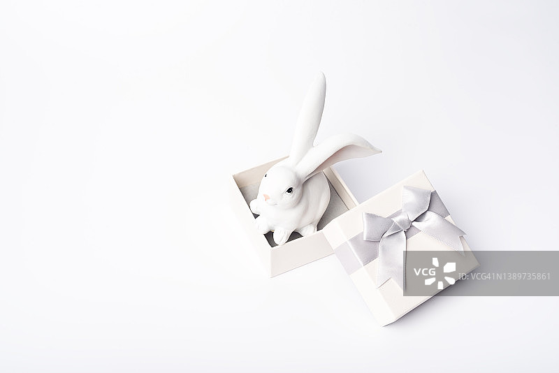 白色玩具复活节在礼物盒上的白色背景。复活节假期概念。单色背景。图片素材