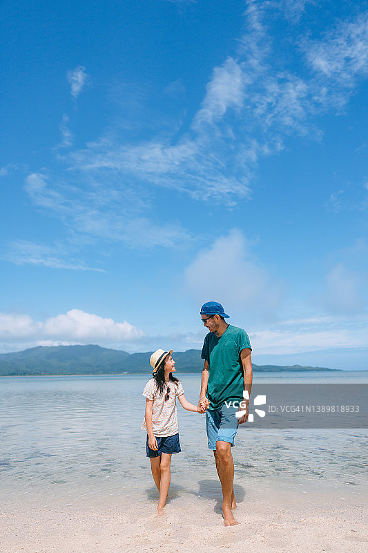 父亲和小女儿站在日本冲绳的热带海滩上图片素材