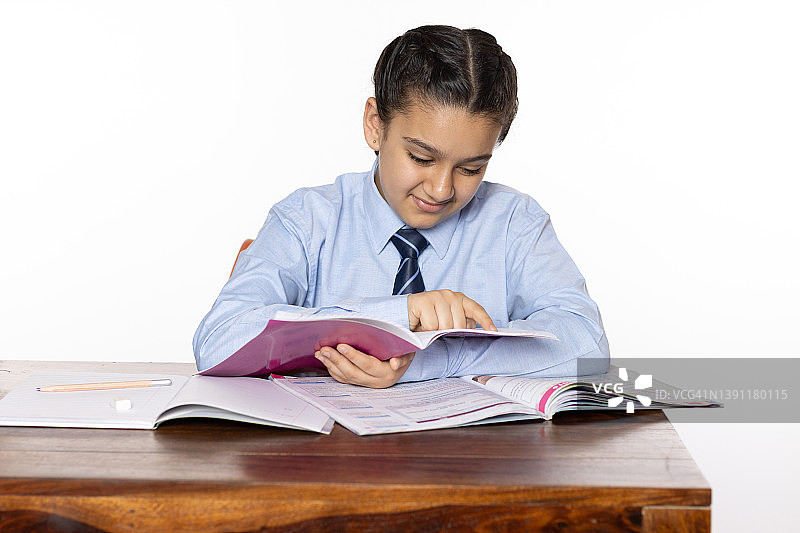 小学的小女孩坐在教室里阅读笔记本孤立的白色背景图片素材