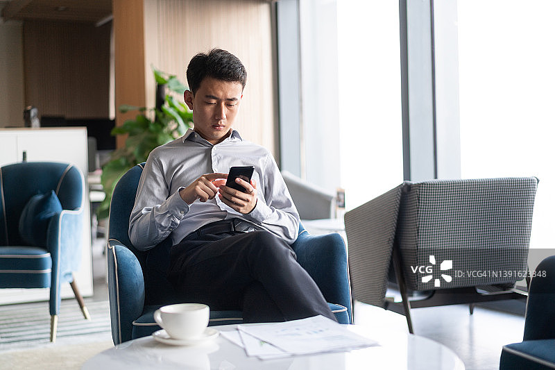 年轻的中国商人在现代办公室使用手机图片素材