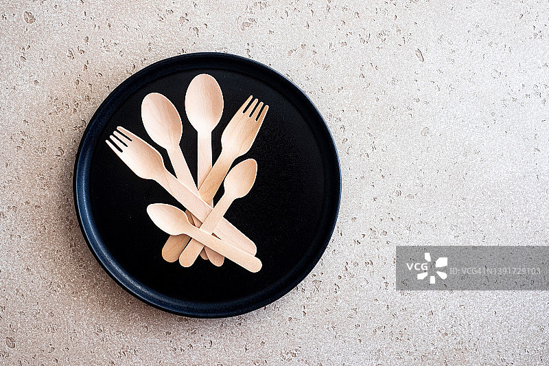 一组木制汤匙，叉子和茶匙在一个黑色的盘子或托盘上的混凝土背景，俯视图。零浪费的概念。副本的空间。图片素材
