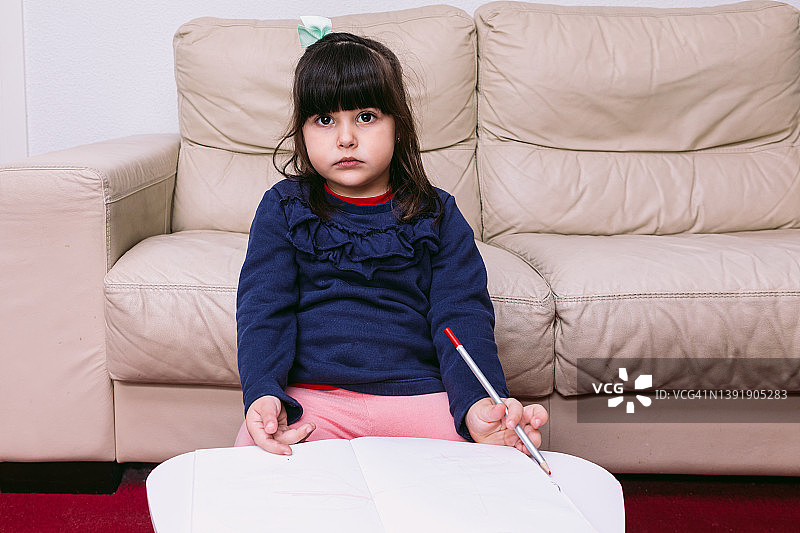 小女孩在家里画画，在笔记本上用红笔，认真的。童年的概念、绘画、成长和想象。图片素材