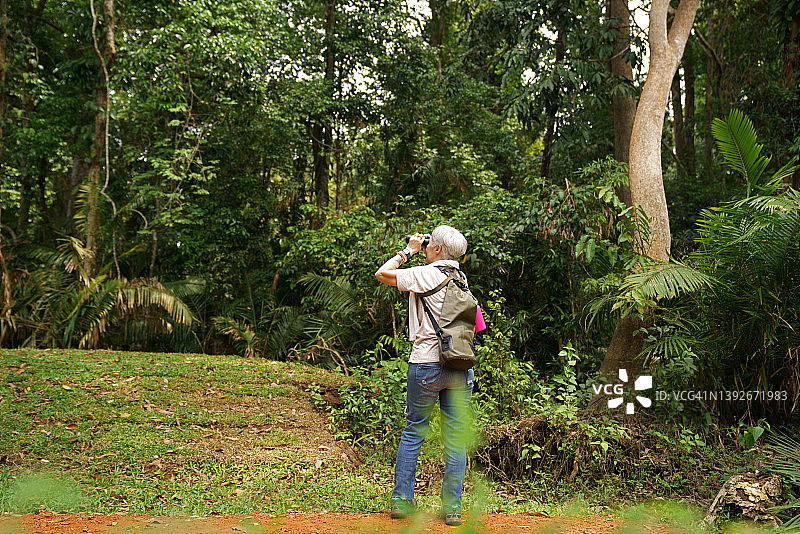 高级妇女背包旅游徒步旅行，探索自然，野生动物，在自然小径拍照图片素材