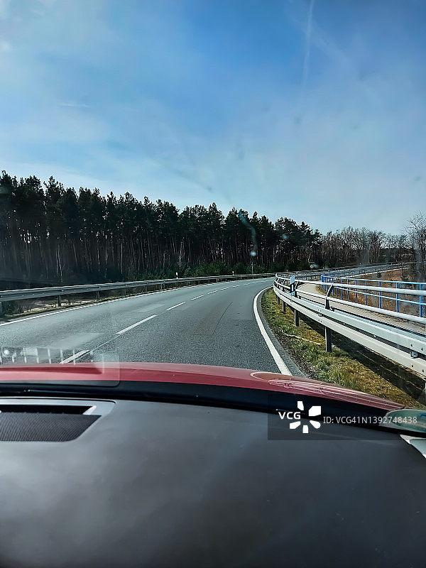 从一辆行驶的汽车上看到有路缘标志的转弯道路图片素材