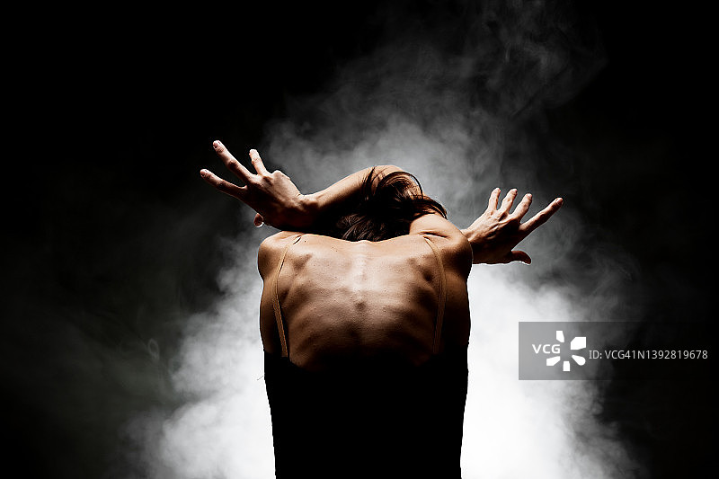 半剪影现代芭蕾舞者摆的黑色背景与烟图片素材