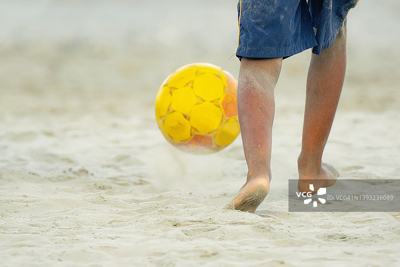 在海滩上踢足球的男孩图片素材