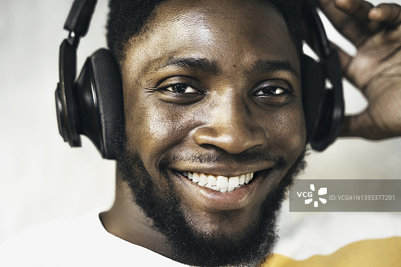 年轻英俊的非洲裔美国人戴着耳机欣赏音乐，特写镜头图片素材