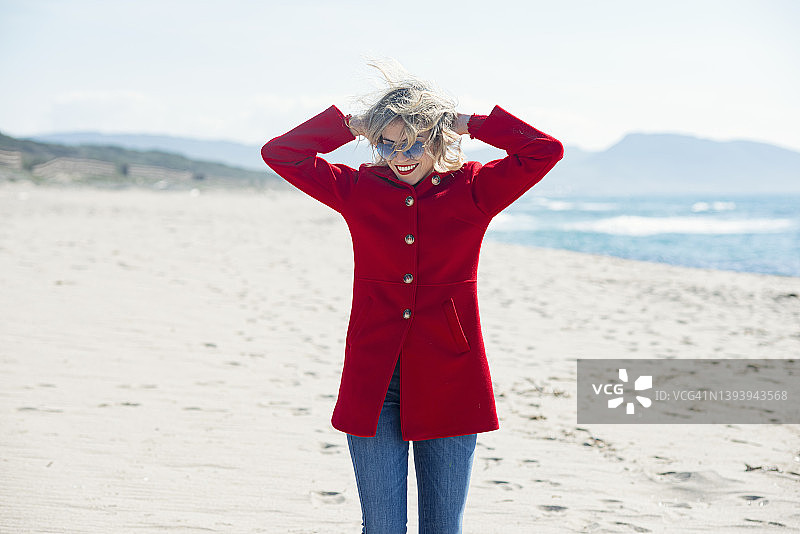 穿红色外套的女人在海滩上玩得很开心图片素材