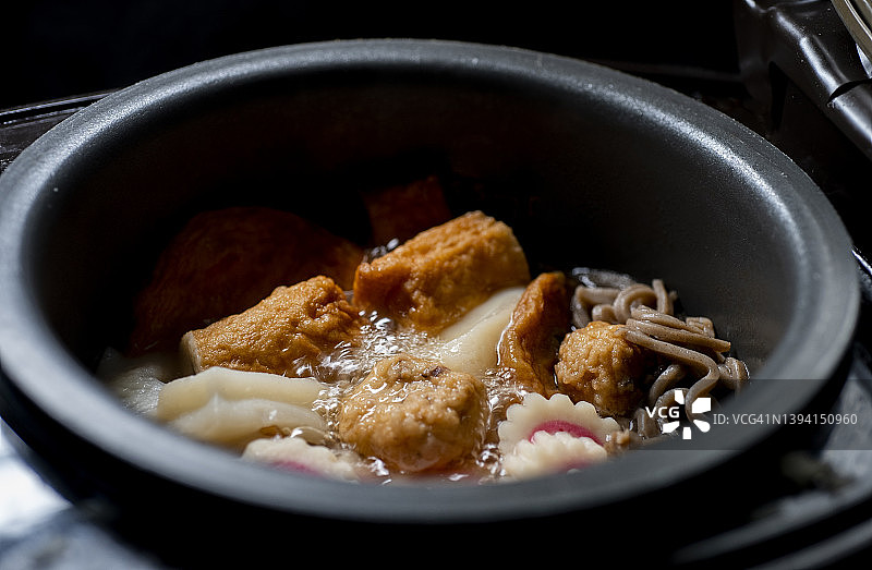 近景日本料理炖肉丸，在铁锅里煮，蒸汽上升。图片素材
