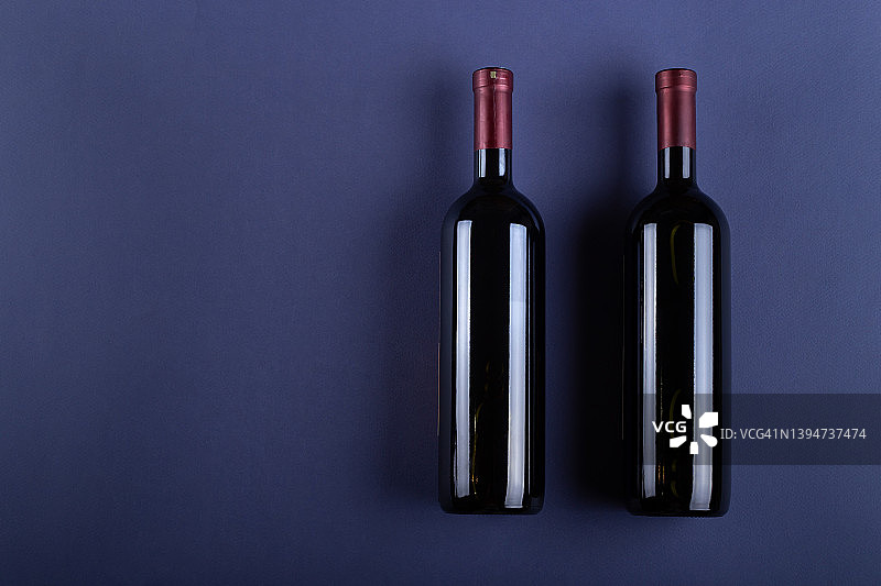 两瓶红酒，没有紫色纸背景上的标签。模拟饮料，标签和短信的位置。图片素材
