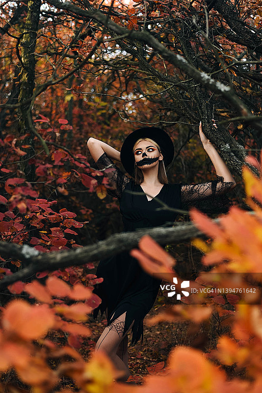 美丽的女孩在万圣节化妆的背景，秋天的森林。万圣节。秋天的森林。图片素材