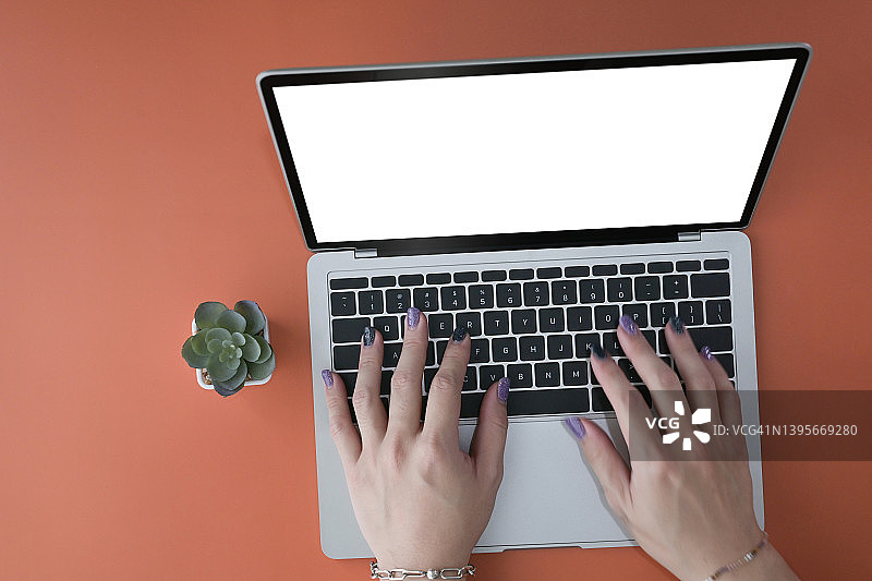 俯视时尚女人的手在笔记本电脑键盘上打字。图片素材