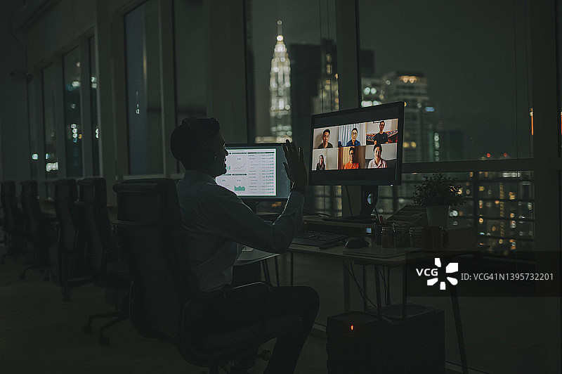 亚洲印度男性白领视频电话工作到很晚在办公室单独在低光与海外同事图片素材