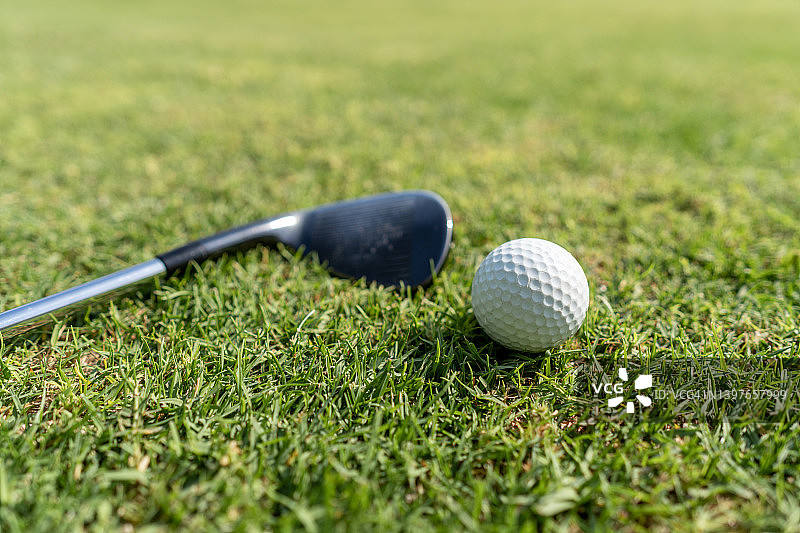 一个高尔夫球棒和一个高尔夫球在草地上图片素材