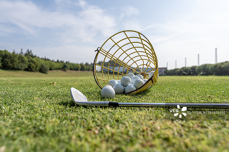 高尔夫球棒:高尔夫球场草坪上的高尔夫球棒和一篮高尔夫球图片素材