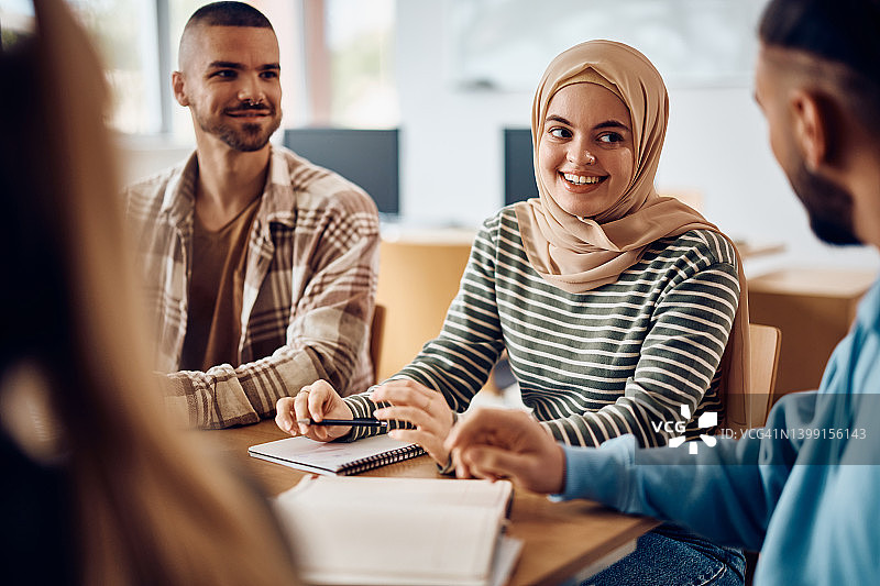 快乐的穆斯林学生与她的同学在大学教室里一起学习。图片素材
