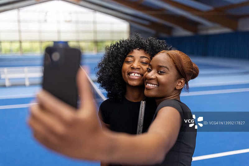 微笑的女子网球运动员在网球场上自拍图片素材