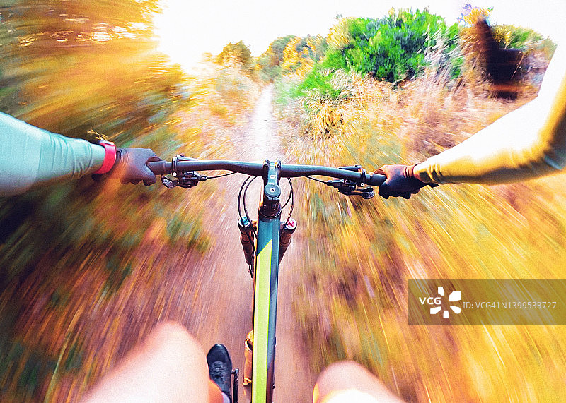 从个人角度骑山地自行车与极端模糊的运动在黄金时间。图片素材