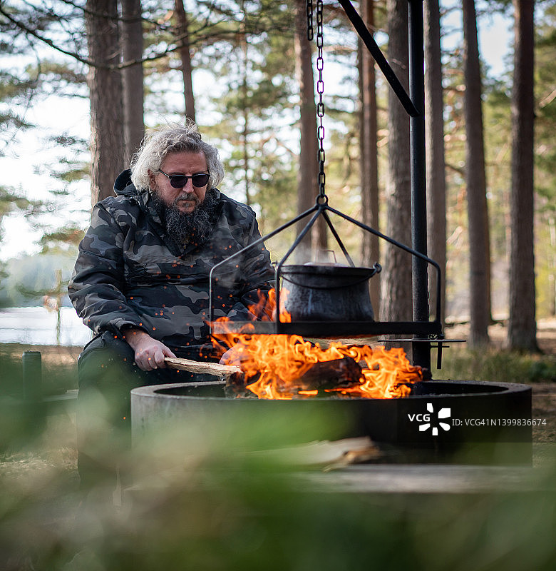 斯堪的那维亚森林里，一名男子用大锅火准备食物图片素材