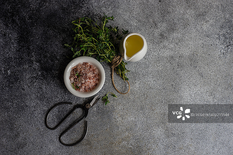 俯瞰一束新鲜的百里香，橄榄油，粉红色的喜马拉雅盐和剪刀图片素材