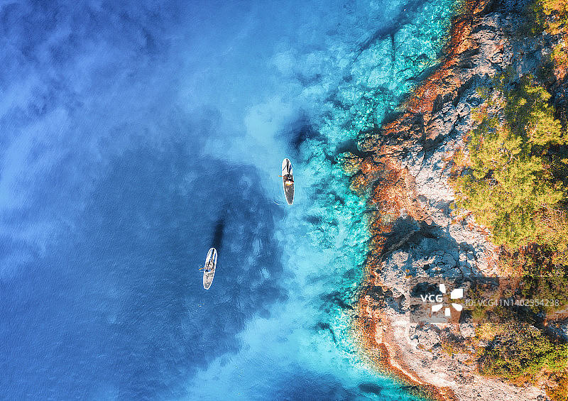 航拍人们在漂浮的sup board上，蓝色的大海，岩石图片素材