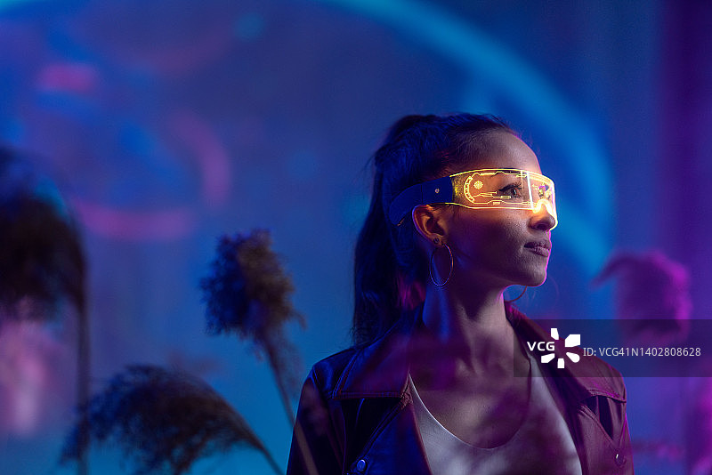 未来的年轻女子在VR环境与智能眼镜。图片素材
