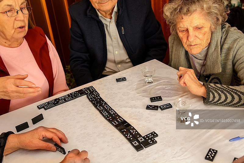 一小群老年人在玩多米诺骨牌。图片素材