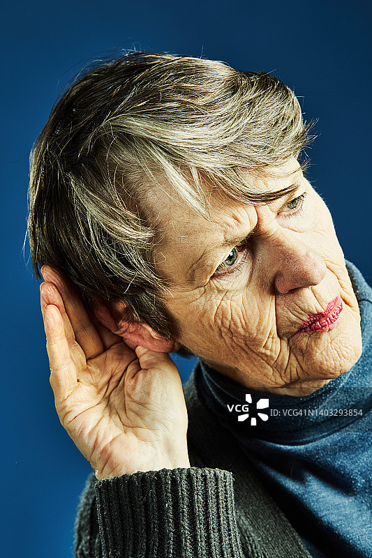 听力不好的老妇人捂着耳朵努力听着什么图片素材