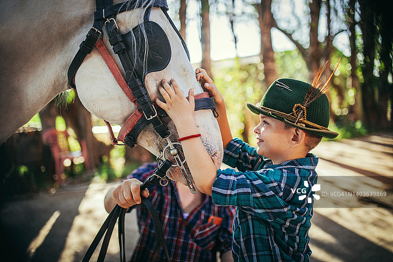 父亲和儿子在农场照顾马匹图片素材