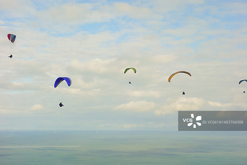 多彩的滑翔伞在多云的海洋上空飞翔图片素材
