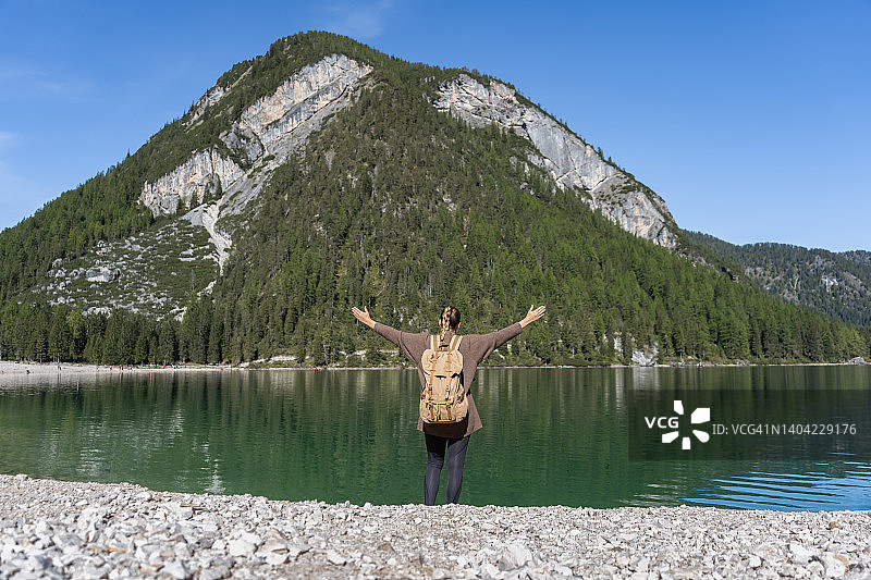 成功的女徒步者欢呼与手臂在高山湖图片素材
