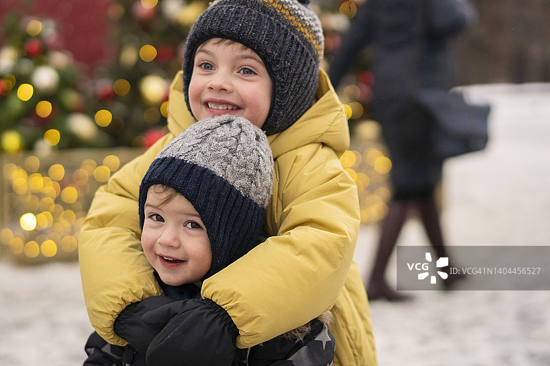 微笑的兄弟在圣诞市场拥抱图片素材
