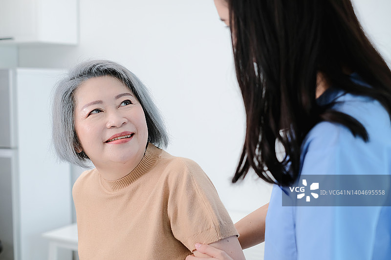 亚洲老年妇女高兴地看着看护者照顾。图片素材