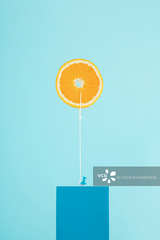蓝色背景上的一片橙色。最小的错觉的概念。夏天和水果的灵感。图片素材