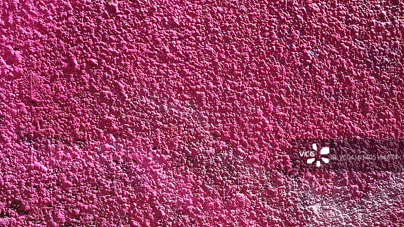 法国巴黎，有纹理的混凝土墙被涂成粉红色，被阳光照亮图片素材