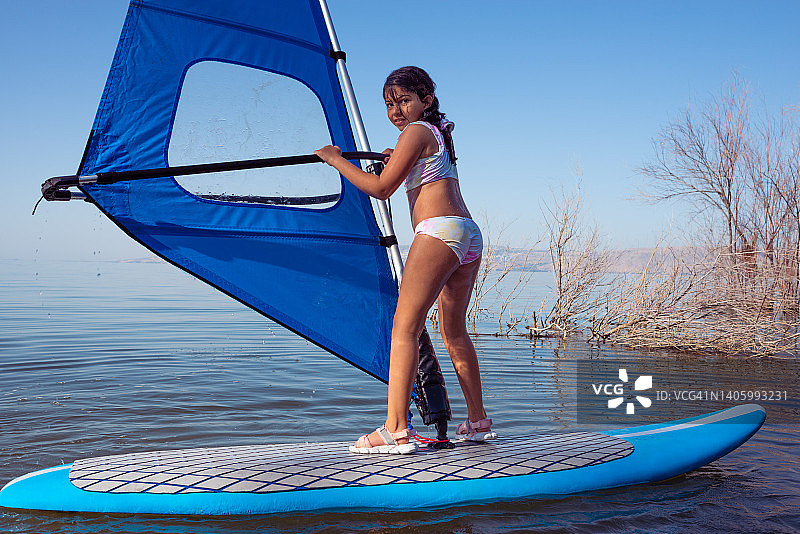 一个上小学的女孩开始学习风帆冲浪。图片素材